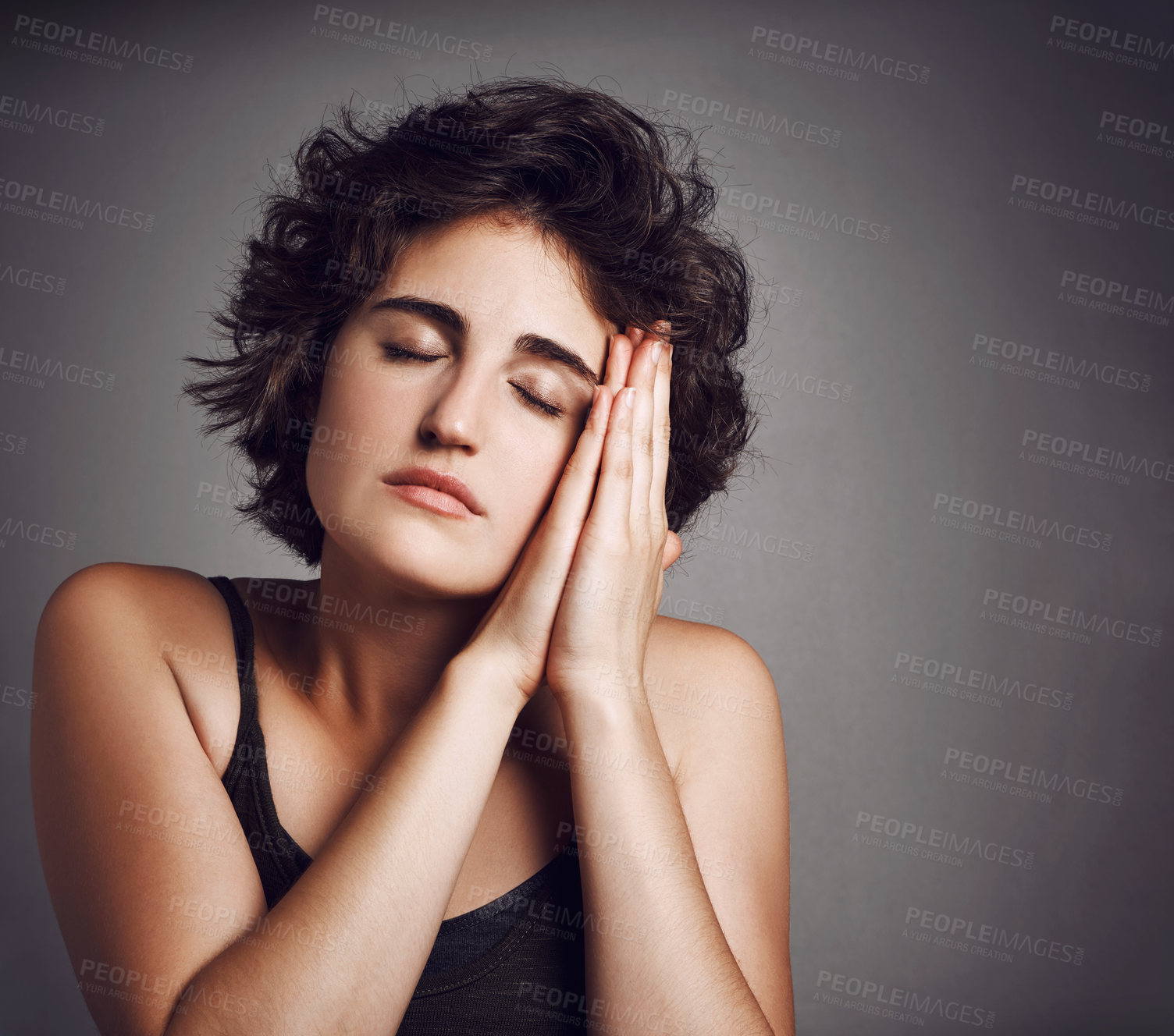 Buy stock photo Studio shot of an attractive young woman sleeping on her hands against a grey background