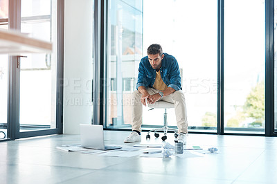 Buy stock photo Shot of a young businessman brainstorming with paperwork on a floor in an office