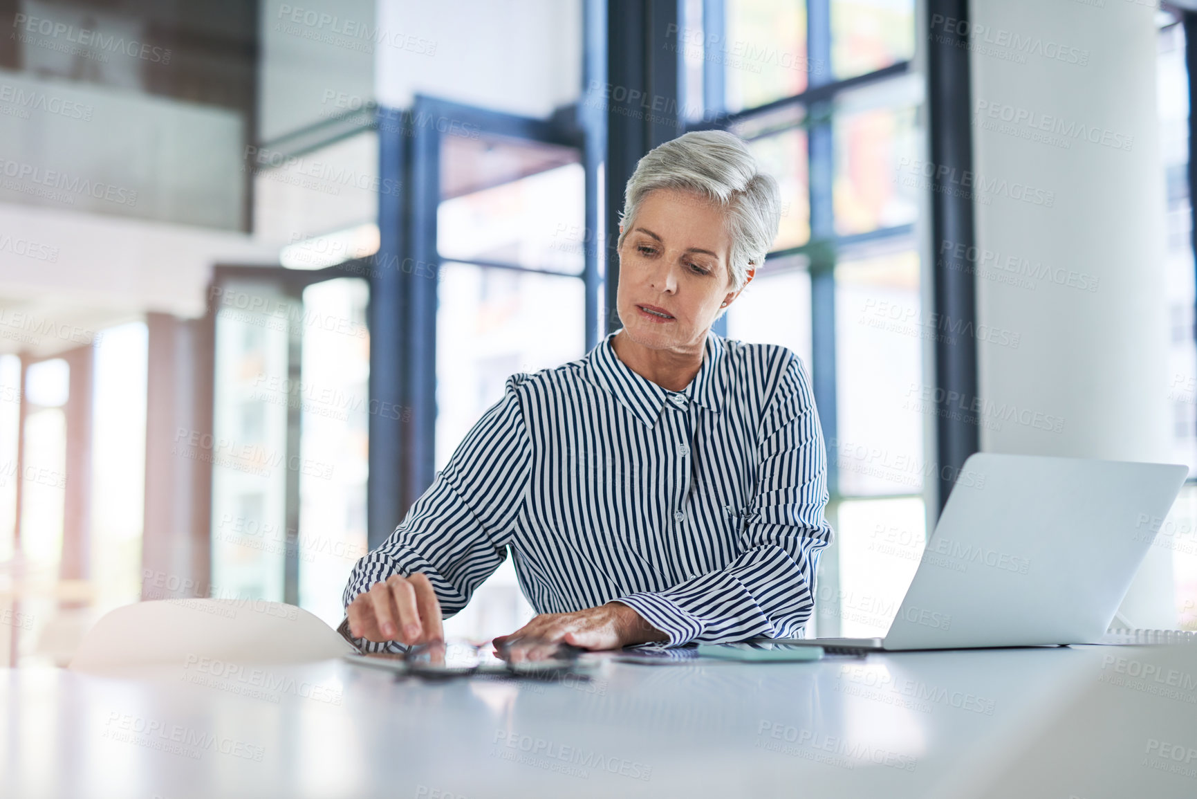 Buy stock photo Shot of a mature businesswoman using a digital tablet at her office desk at work