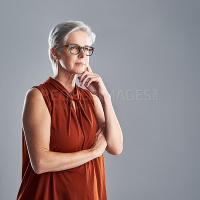Buy stock photo Shot of an attractive mature woman looking very thoughtful against a grey background