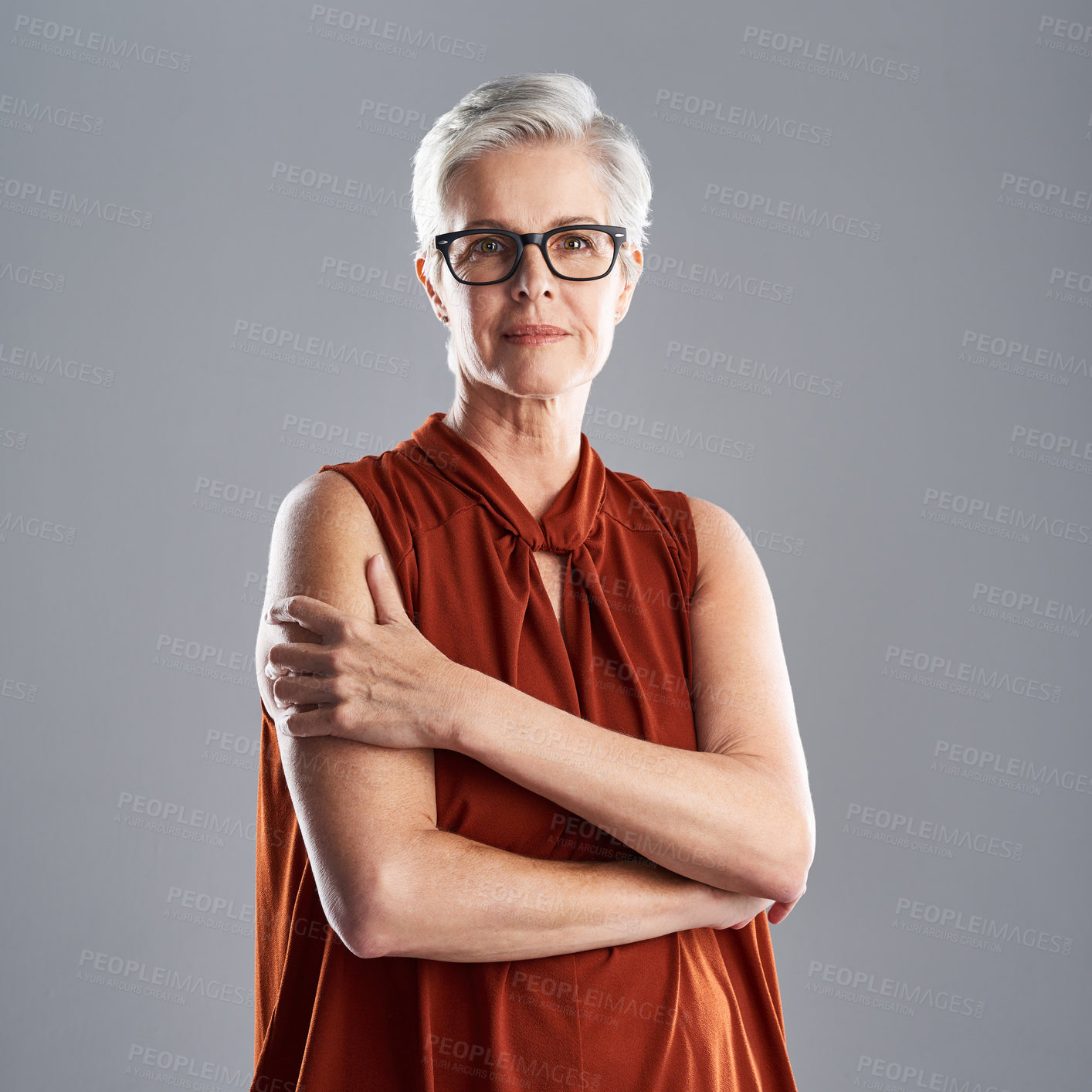 Buy stock photo Portrait of an attractive mature businesswoman posing with her arms folded against a grey background