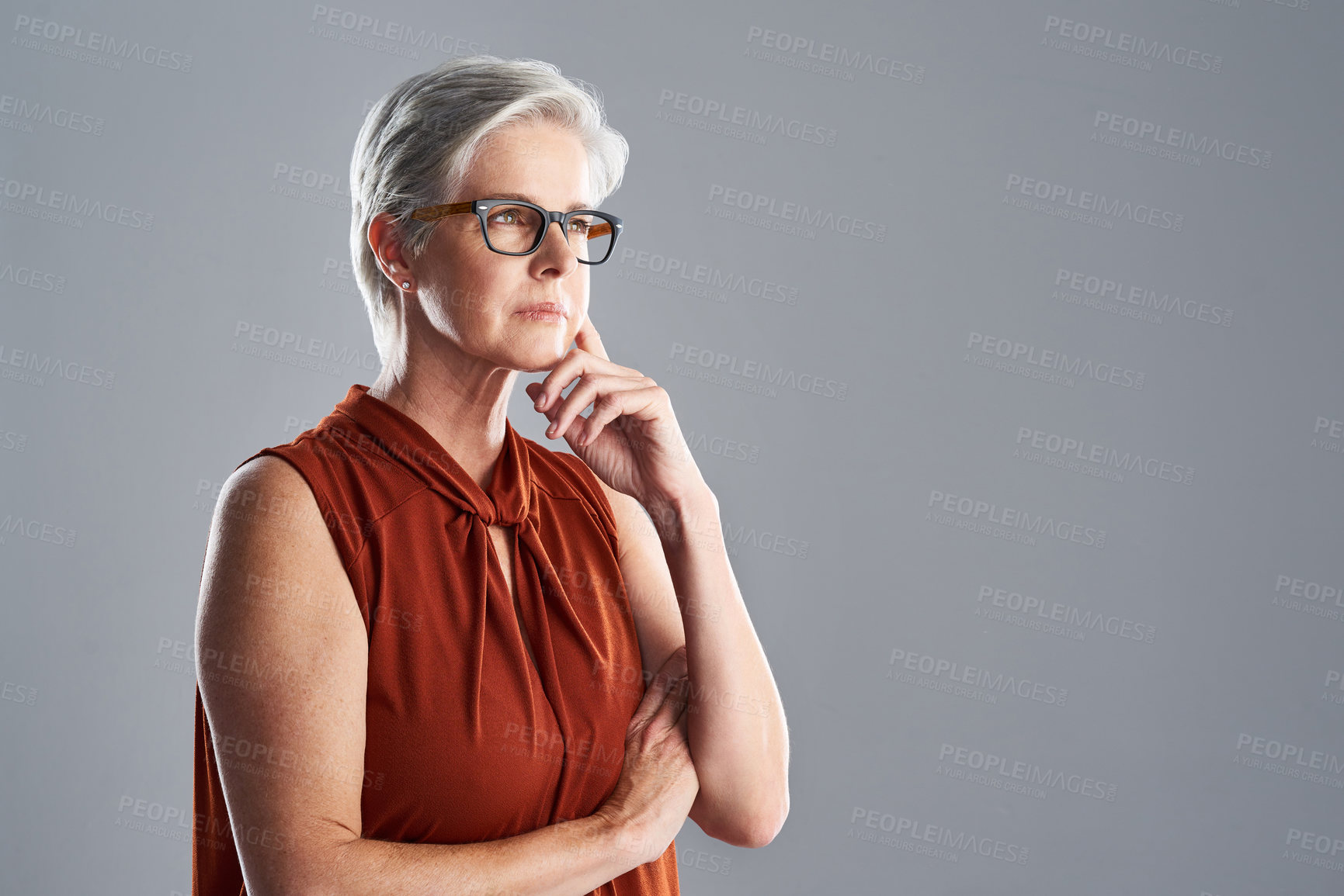 Buy stock photo Shot of an attractive mature woman looking very thoughtful against a grey background