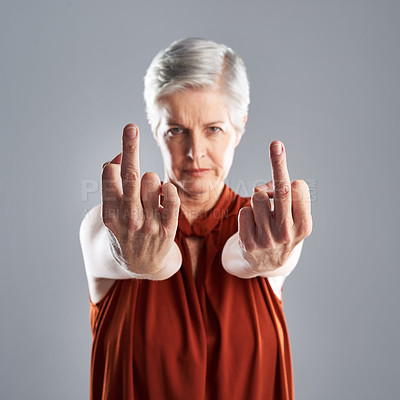 Buy stock photo Hand gesture, portrait and rude with senior woman in studio on gray background for disrespect. Anger, emoji and obscene with unhappy mature person showing middle finger for conflict or protest