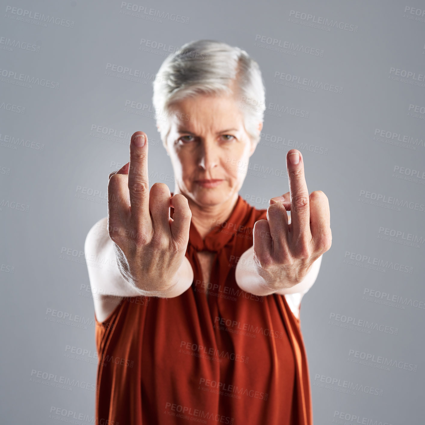 Buy stock photo Portrait of mature woman showing the middle finger against a grey background