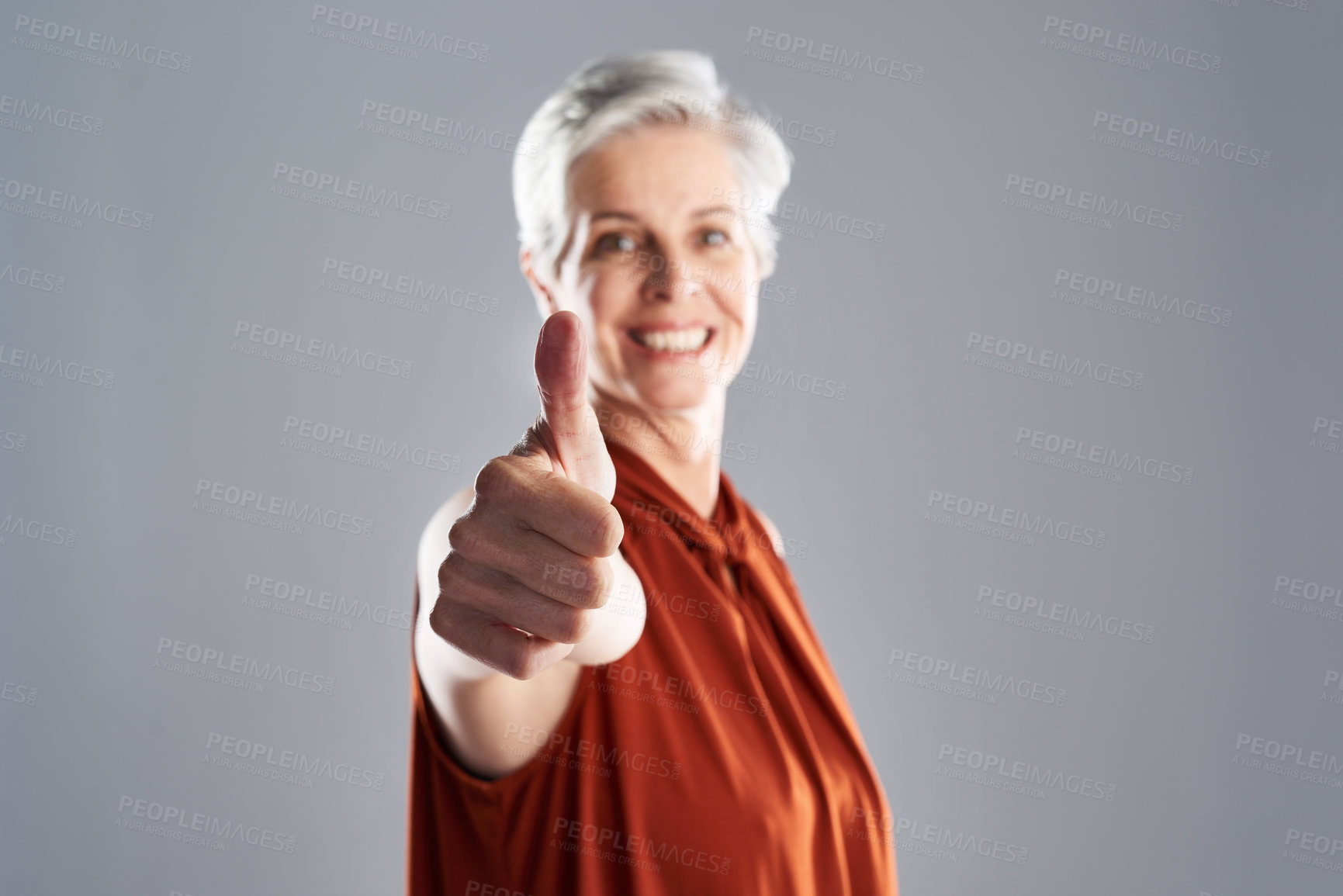 Buy stock photo Portrait of an attractive mature businesswoman posing with her thumbs up against a grey background