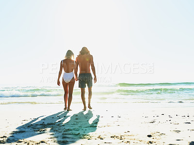 Buy stock photo Rearview shot of a young couple enjoying some quality time together at the beach