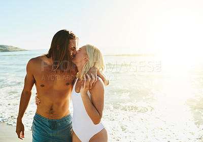 Buy stock photo Shot of an affectionate young couple kissing each other at the beach