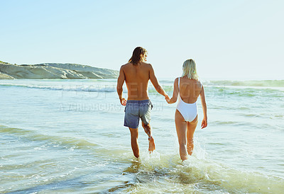 Buy stock photo Rearview shot of a young couple enjoying some quality time together at the beach