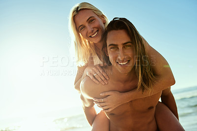 Buy stock photo Portrait of a young man giving his girlfriend a piggyback ride at the beach
