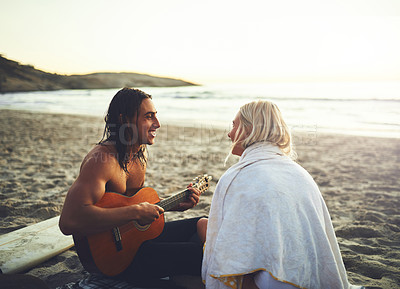 Buy stock photo Shot of a young happy couple serenading each other during a date on the beach at sunset