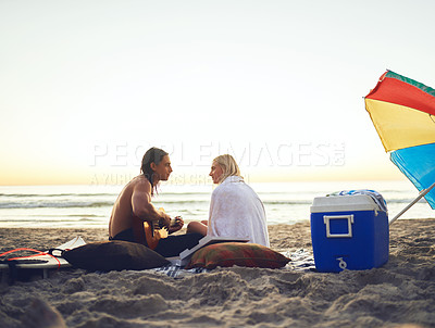 Buy stock photo Rearview shot of an affectionate young couple serenading each other during a date on the beach at sunset