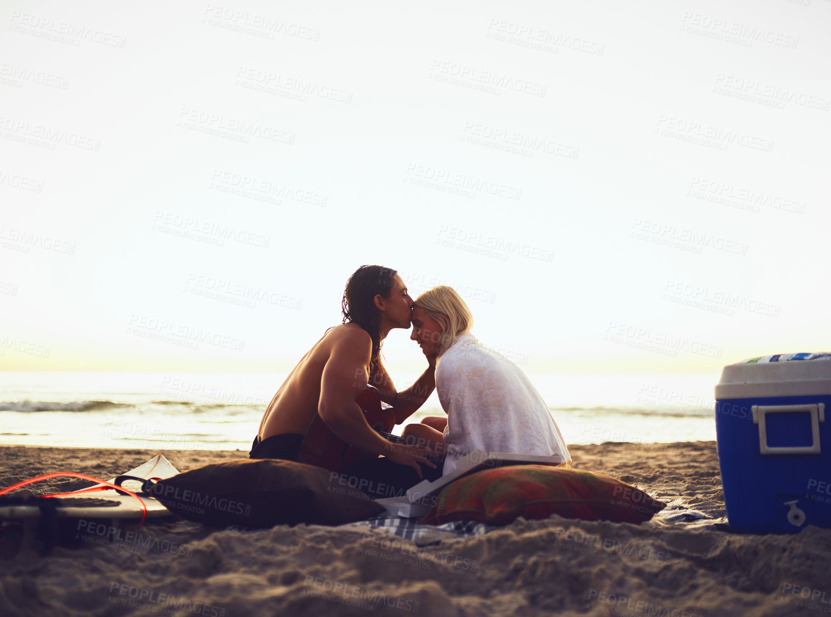 Buy stock photo Shot of a young affectionate couple sharing a tender moment during a date on the beach at sunset