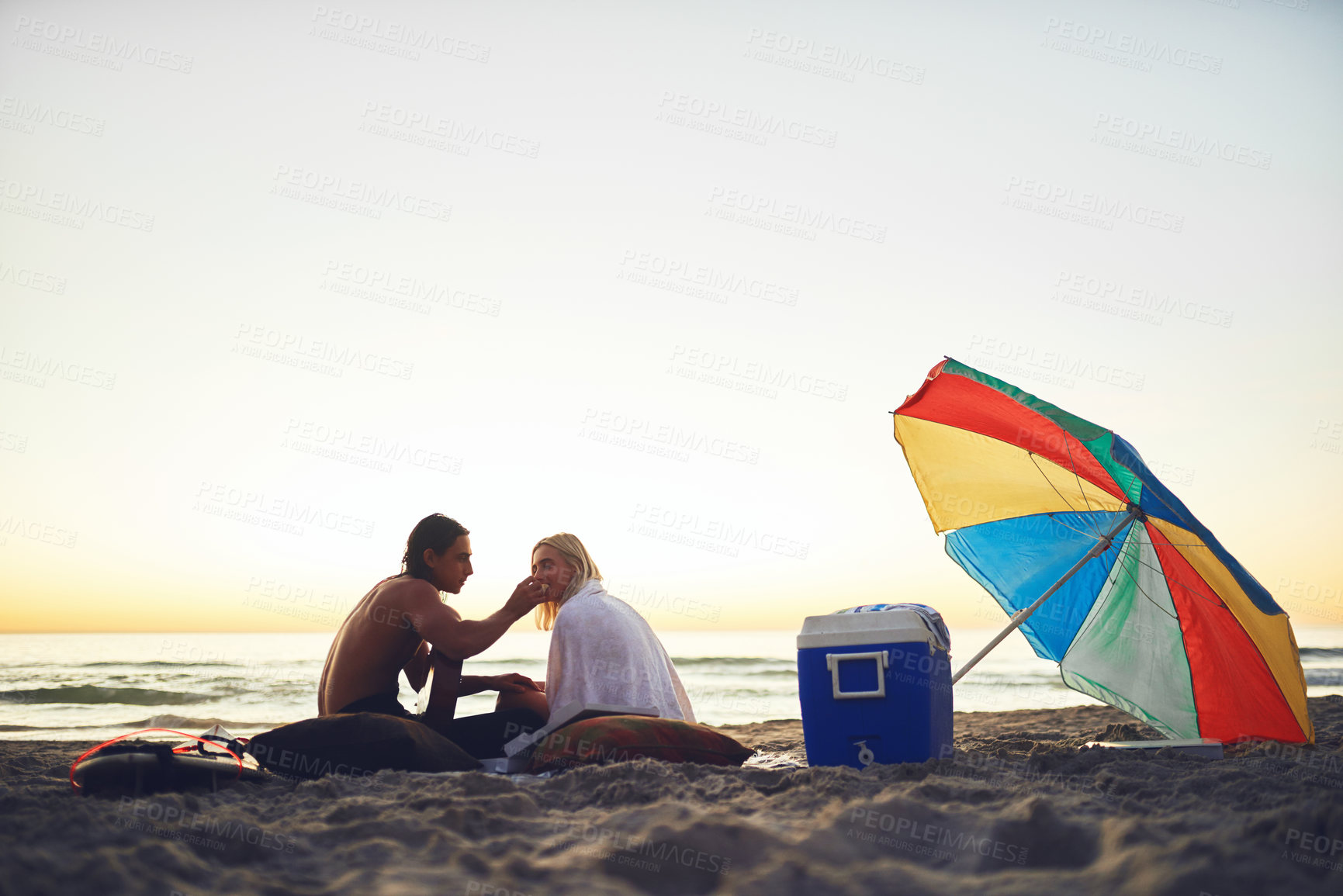 Buy stock photo Beach, couple and feeding food at picnic at sunset on vacation date, relax and romantic holiday. Eating pizza, man and woman by ocean for travel, play guitar and love music on mockup space in summer