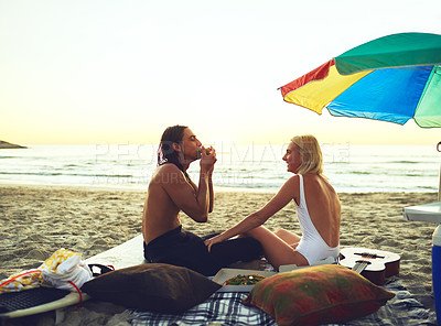 Buy stock photo Beach picnic, summer and happy couple eating pizza on holiday date, relax and romantic vacation at sunset. Food, man and woman by ocean together by umbrella for travel, smile or love on mockup space