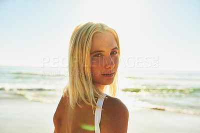 Buy stock photo Cropped portrait of an attractive young female looking over her shoulder on the beach at sunset