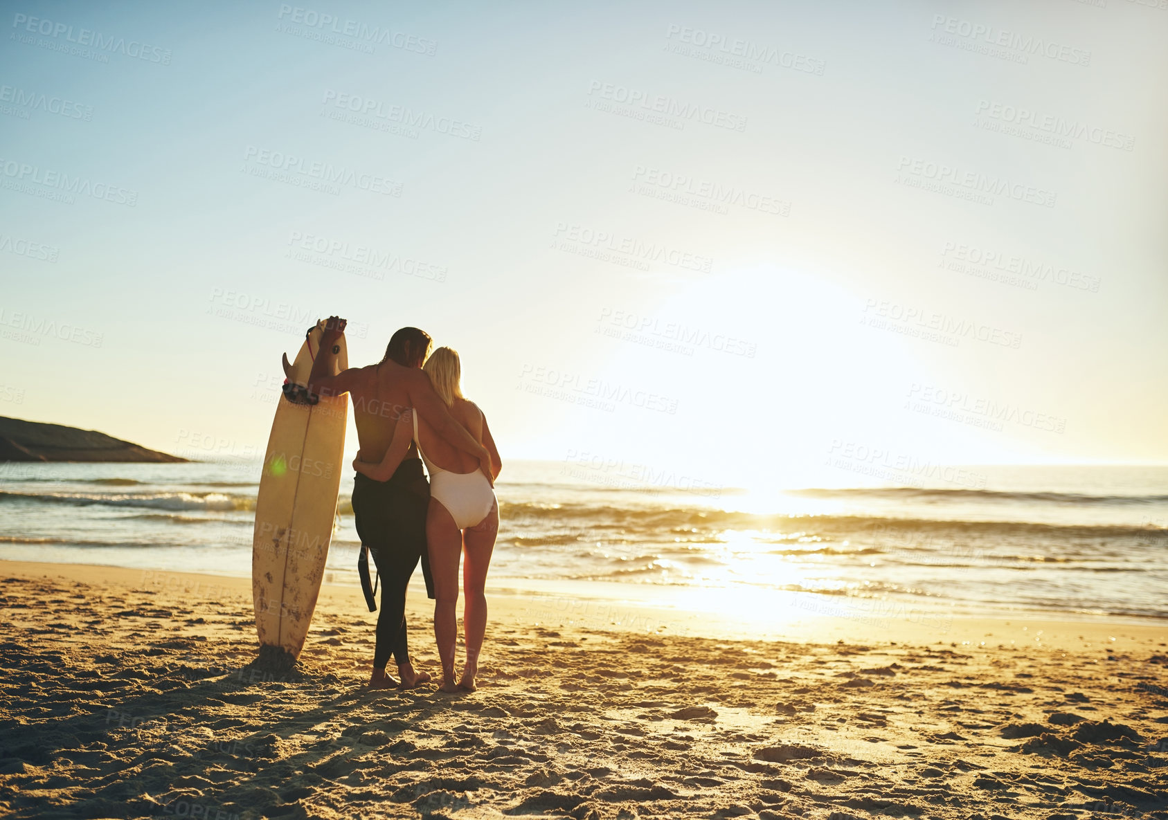 Buy stock photo Rearview shot of an unrecognizable young couple standing and holding each other on the beach at sunset