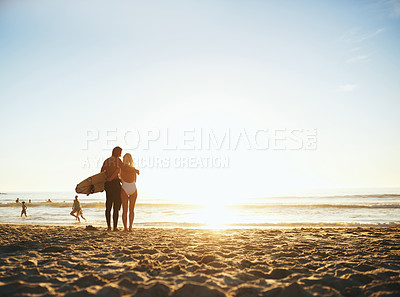 Buy stock photo Cropped rearview shot of an unrecognizable young couple with a surfboard standing and holding each other on the beach