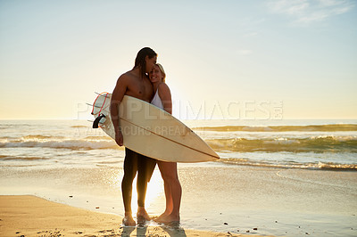 Buy stock photo Full length shot of a happy young couple with a surfboard sharing a tender moment on the beach at sunset