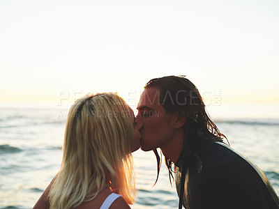 Buy stock photo Cropped shot of an affectionate  young couple kissing on the beach at sunset against a background of the ocean