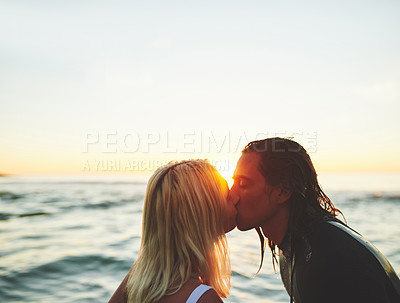 Buy stock photo Cropped shot of an affectionate young couple kissing on the beach at sunset against a background of the ocean