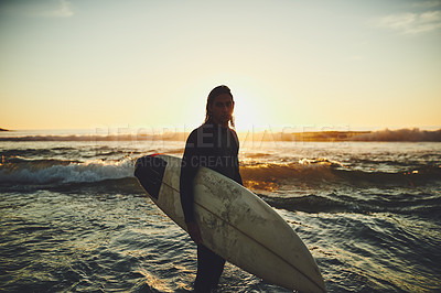 Buy stock photo Portrait of a young man carrying a surfboard at the beach