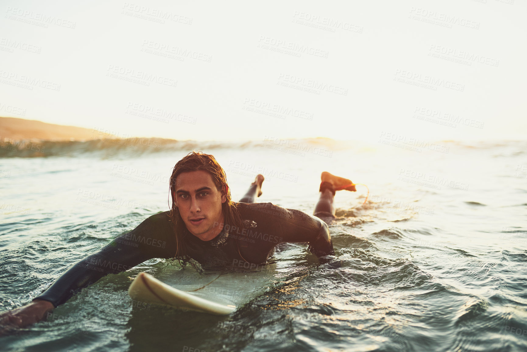 Buy stock photo Portrait of a young man paddling on a surfboard in the sea