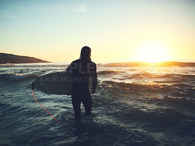 Buy stock photo Rearview shot of a young man carrying a surfboard at the beach