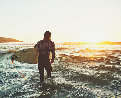 Buy stock photo Rearview shot of a young man carrying a surfboard at the beach