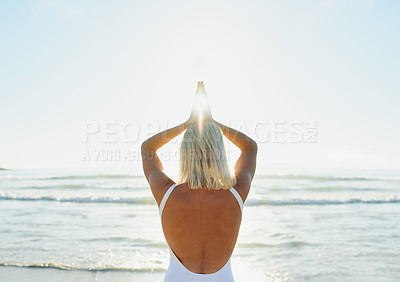 Buy stock photo Cropped shot of an unrecognizable woman in a swimsuit doing yoga early in the morning on the beach