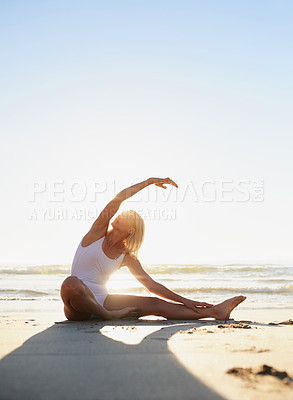Buy stock photo Full length shot of an attractive young woman doing a yoga stretch early in the morning on the beach