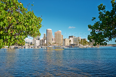 Buy stock photo Apartments or business district beside a beach on a sunny day with a cloudy blue sky and trees framing copyspace. Popular summer vacation tourist location in Hawaii. Luxury resort by ocean in the USA