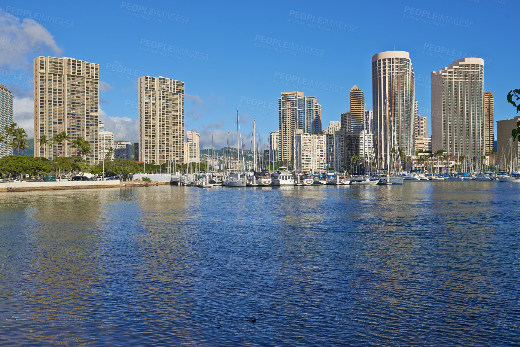 Buy stock photo Apartments or business districts beside a harbour on a sunny day with a cloudy blue sky. A popular summer vacation tourist location in Hawaii. Luxury resort by the ocean in the USA on a tropical sea