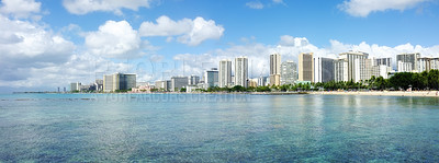 Buy stock photo Apartments or business district beside a beach on a sunny day with a cloudy blue sky. A popular summer vacation tourist location in Hawaii. Luxury resort by the ocean in the USA.