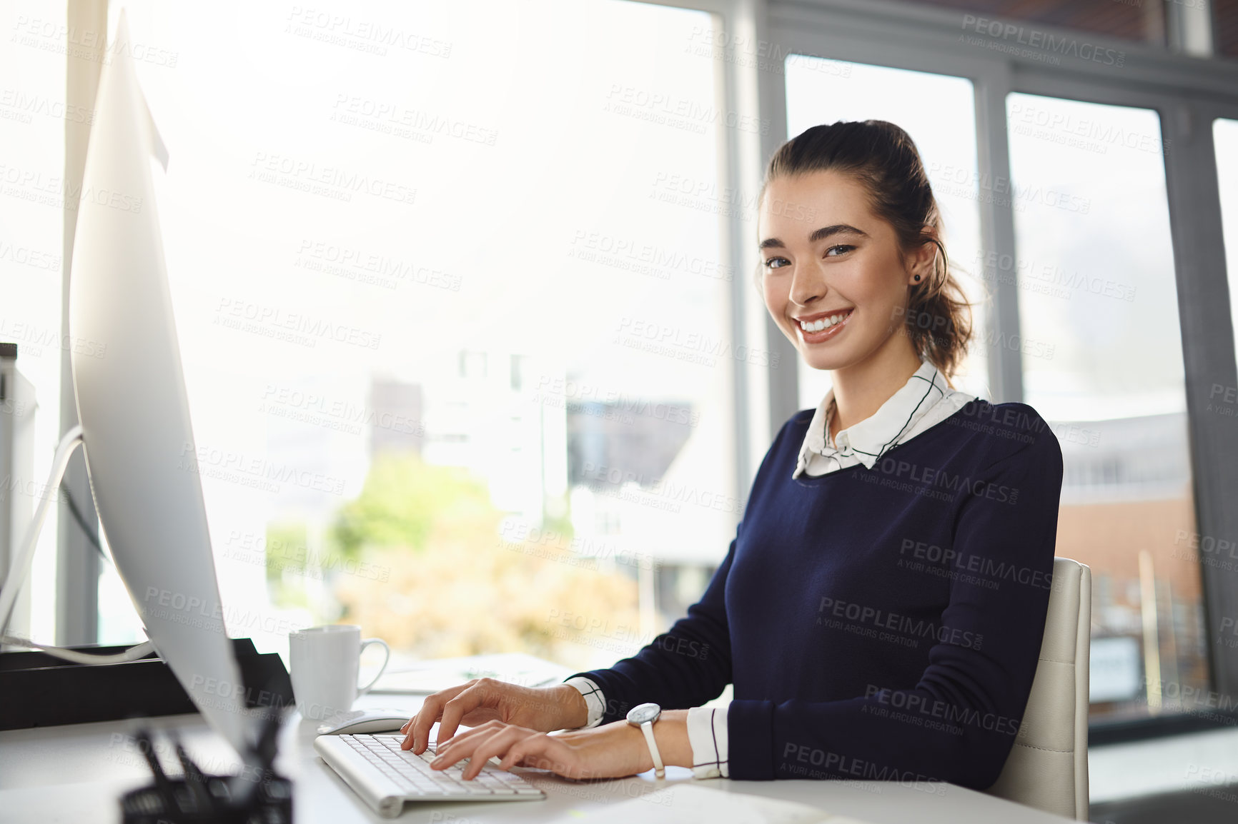 Buy stock photo Portrait of an attractive young businesswoman sitting at her desk and using her computer in a modern office