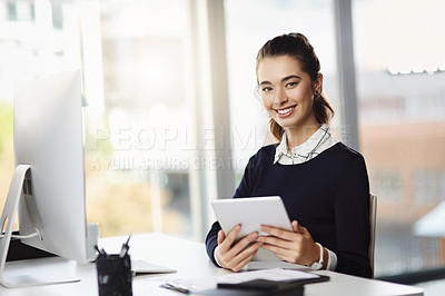Buy stock photo Portrait of an attractive young businesswoman sitting at her desk and using a tablet in a modern office