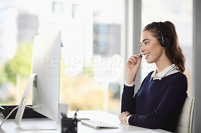 Buy stock photo Shot of an attractive young businesswoman smiling while wearing a headset and sitting at her desk in a modern office