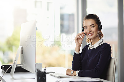 Buy stock photo Portrait of a smiling attractive young businesswoman wearing a headset and sitting at her desk in a modern office