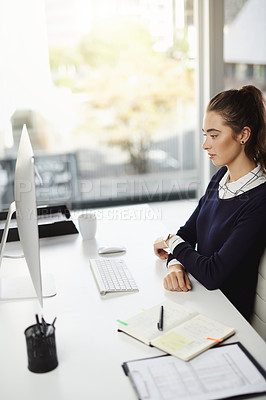 Buy stock photo Shot of an attractive young businesswoman sitting at her desk and looking at her computer screen in a modern office