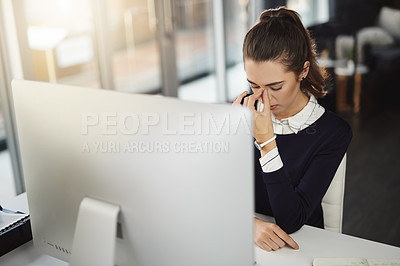 Buy stock photo Shot of an attractive young businesswoman sitting at her desk and feeling stressed in a modern office
