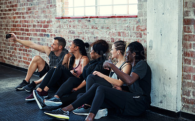 Buy stock photo Shot of a cheerful young group of people sitting down on the floor and taking a self portrait together in a gym