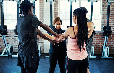 Buy stock photo Shot of a focused young group of people forming a huddle together while one looks into the camera before a workout in a gym