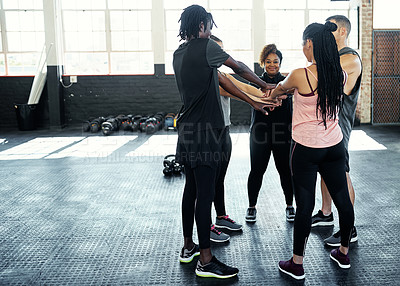 Buy stock photo Shot of a cheerful young group of people forming a huddle together while one looks at the camera before a workout session in a gym