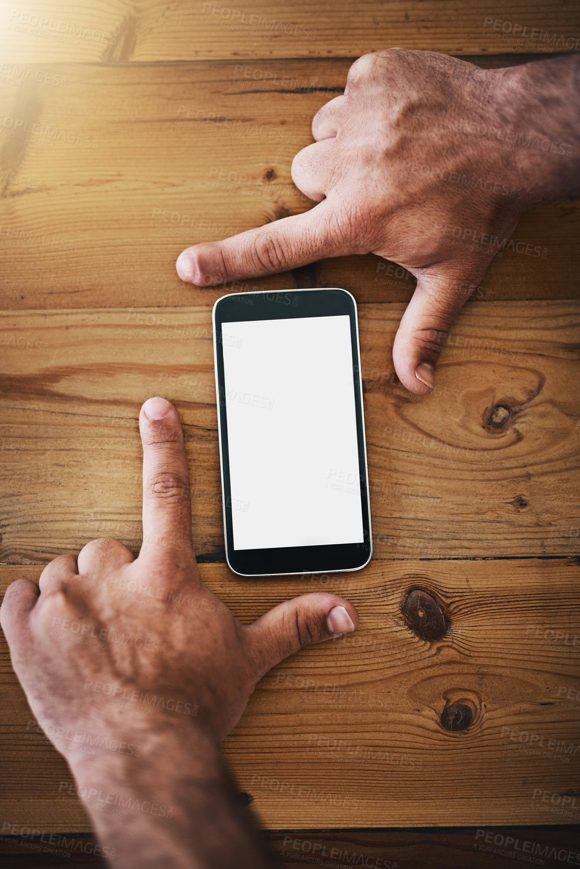 Buy stock photo Cropped shot of an unrecognizable businessman framing a mobile phone on a desk