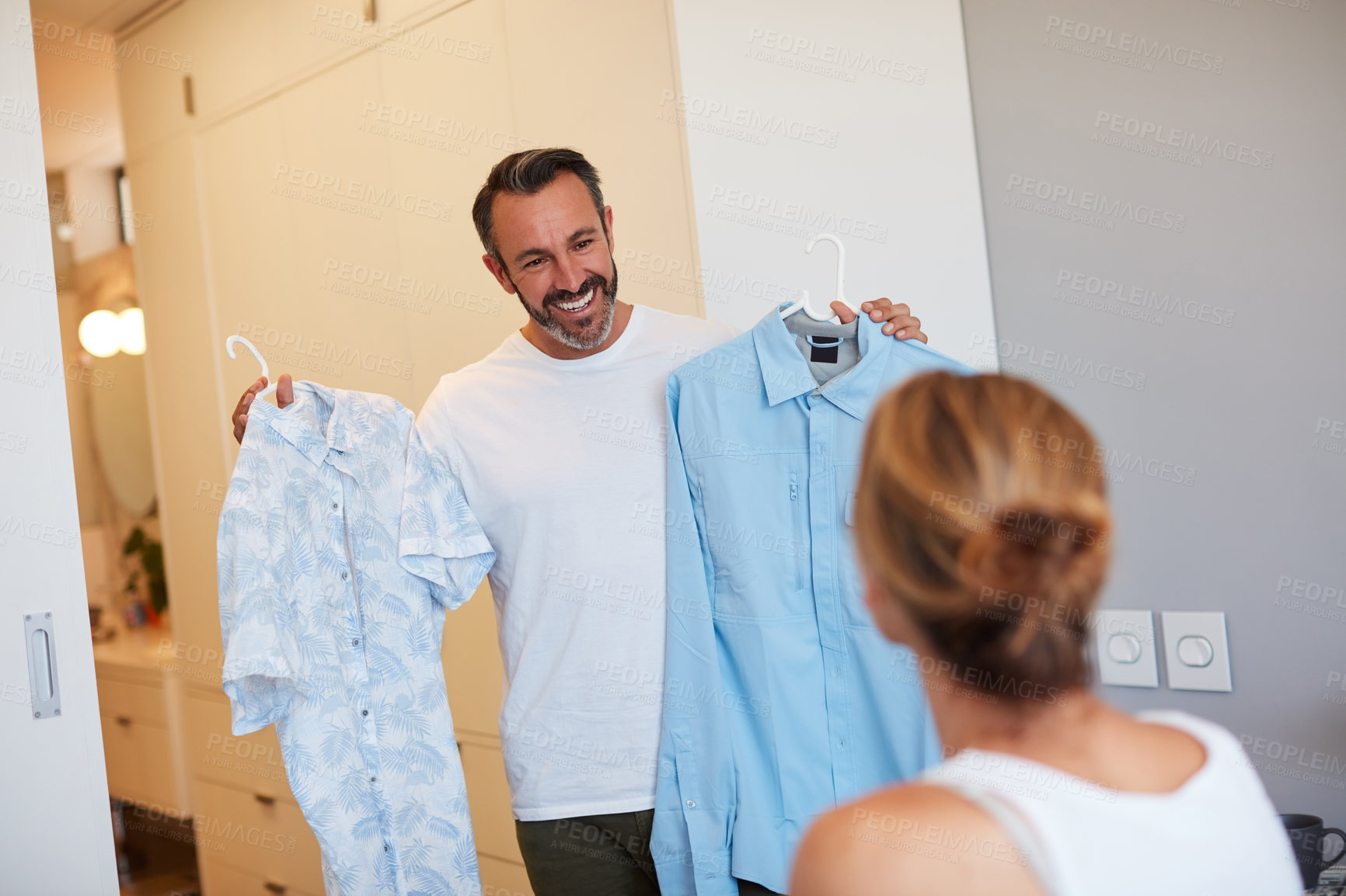 Buy stock photo Cropped shot of a handsome mature man asking his wife's opinion on which shirt to wear