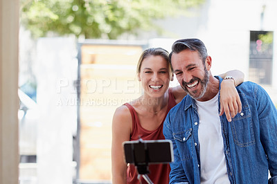 Buy stock photo Cropped shot of an affectionate couple taking a selfie together with a selfie stick outdoors