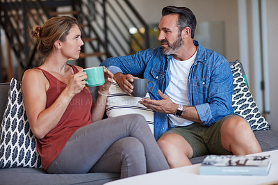 Buy stock photo Cropped shot of a middle aged couple having a discussion while having coffee in their living room at home