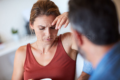 Buy stock photo Cropped shot of an attractive young woman looking hesitant while having a serious conversation with her husband at home