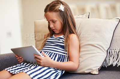 Buy stock photo Girl, child and relax with tablet on sofa for online streaming, games and watching educational videos at home. Yong kid on couch on digital technology, web or app for reading ebook or e learning