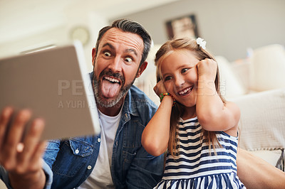 Buy stock photo Shot of an adorable little girl taking selfies with her father on a digital tablet at home