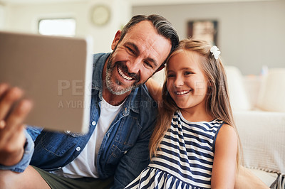 Buy stock photo Shot of an adorable little girl taking selfies with her father on a digital tablet at home